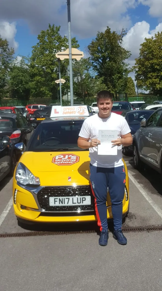 Learner celebrating a driving test pass beside PJ's lesson car