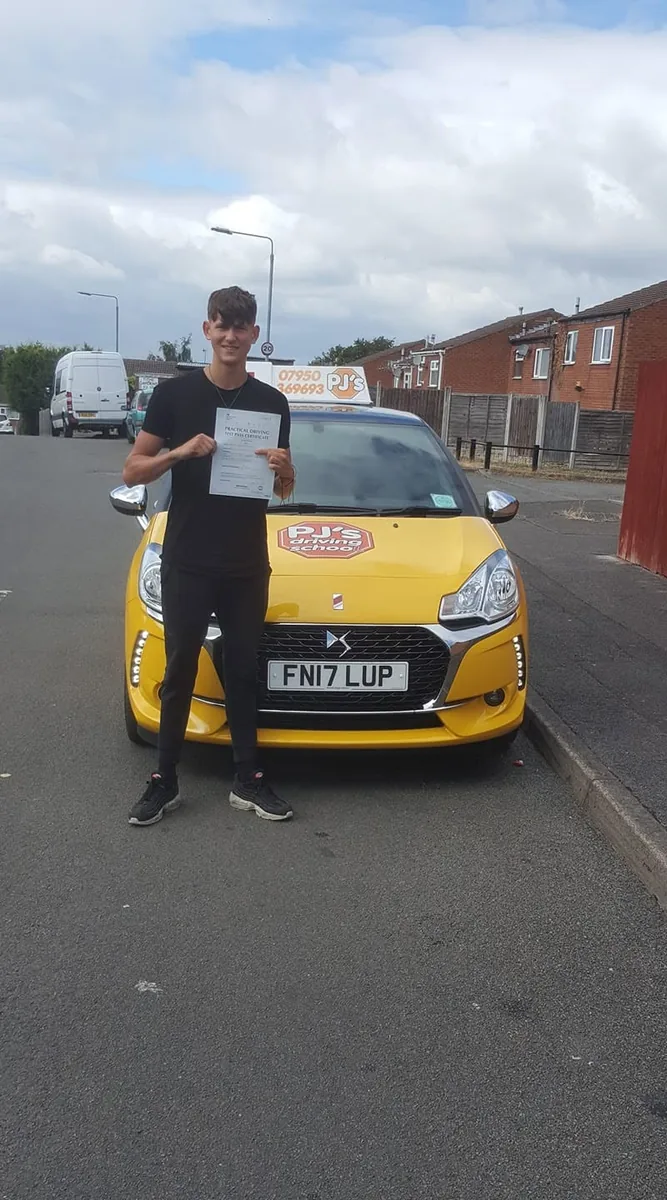 Learner celebrating a driving test pass beside PJ's lesson car