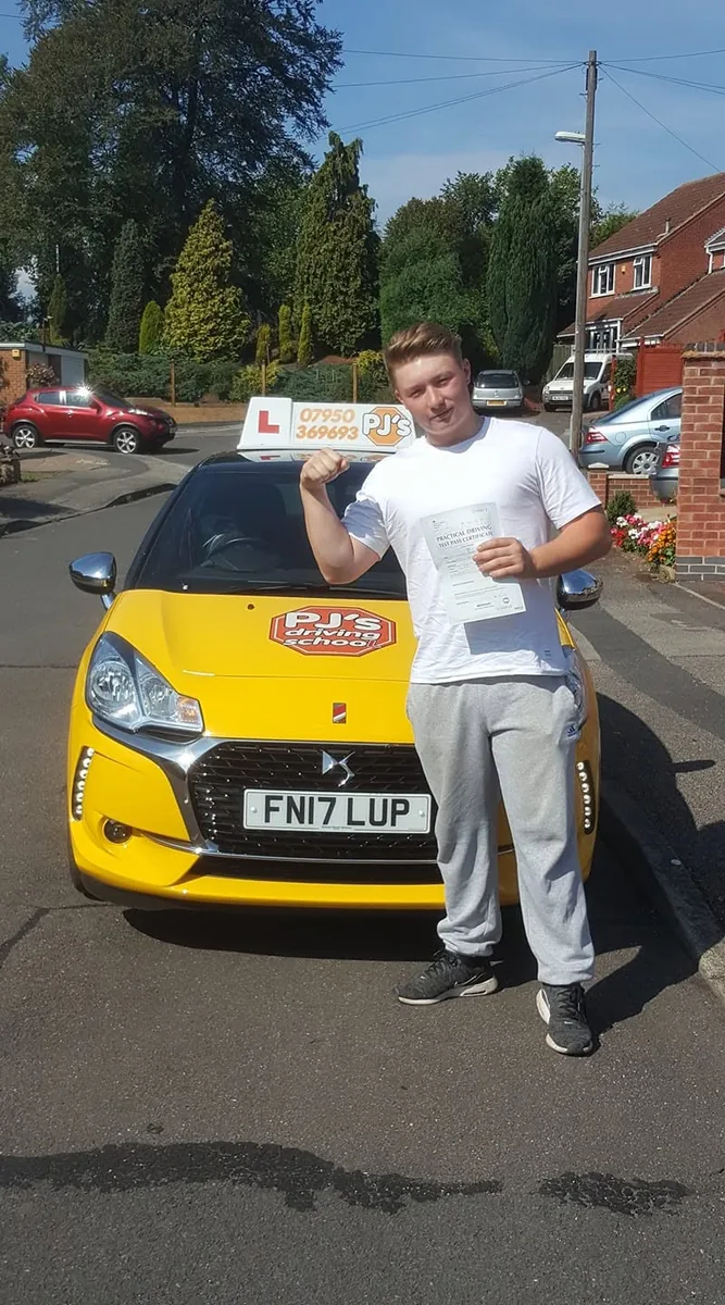 Learner celebrating a driving test pass beside PJ's lesson car