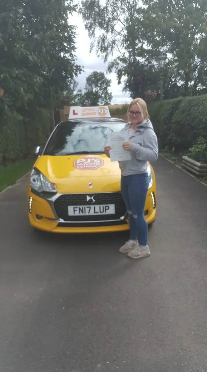 Learner celebrating a driving test pass beside PJ's lesson car