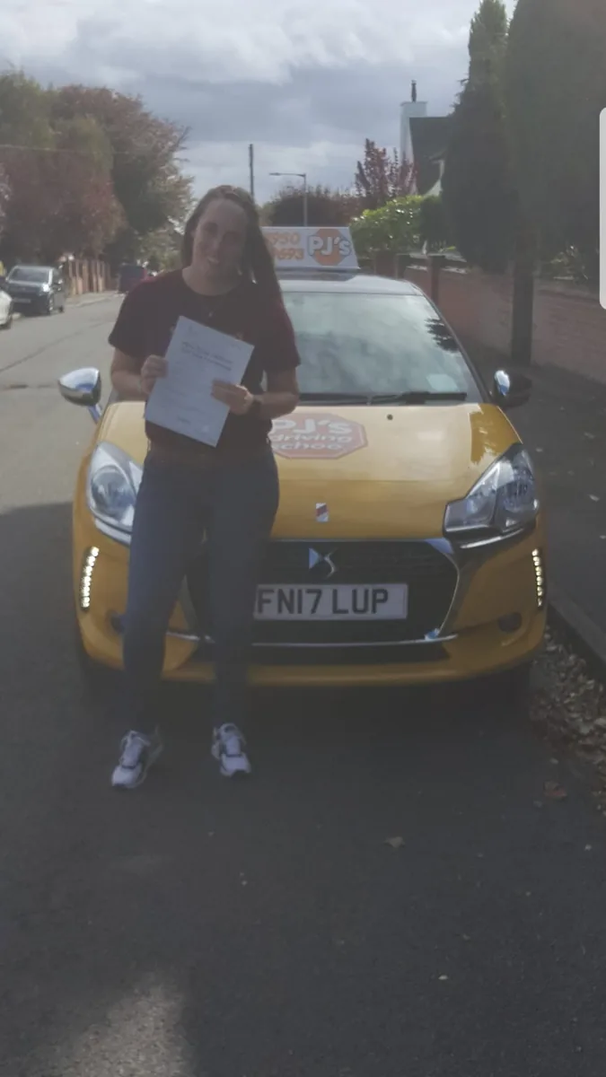 Learner celebrating a driving test pass beside PJ's lesson car