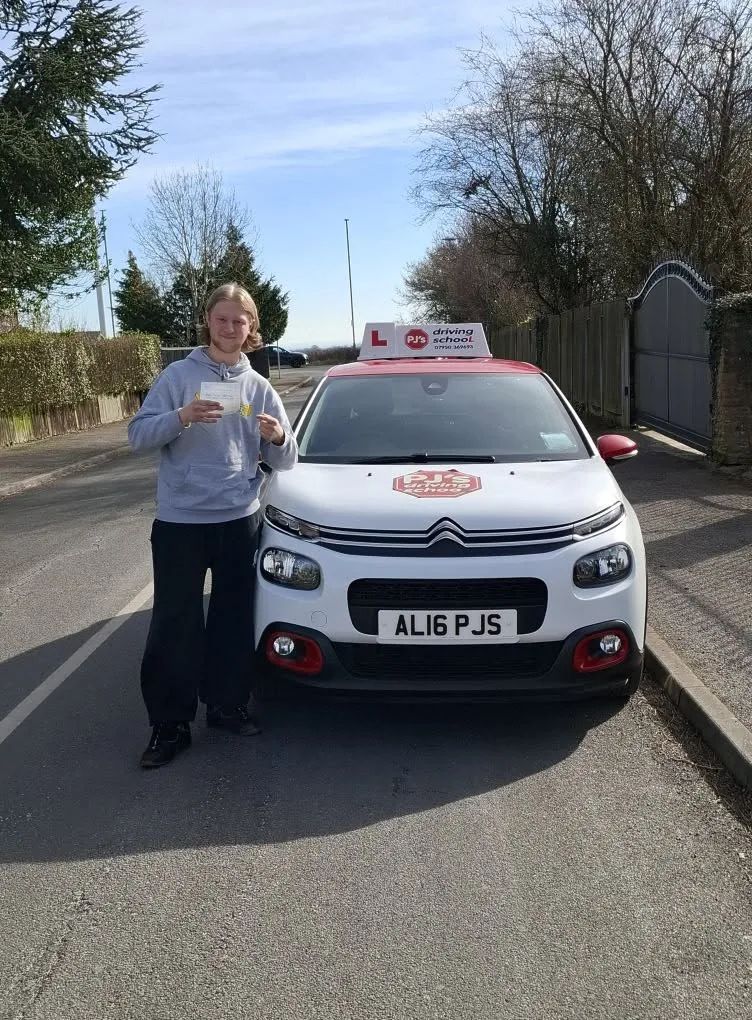 Learner celebrating a driving test pass beside PJ's lesson car