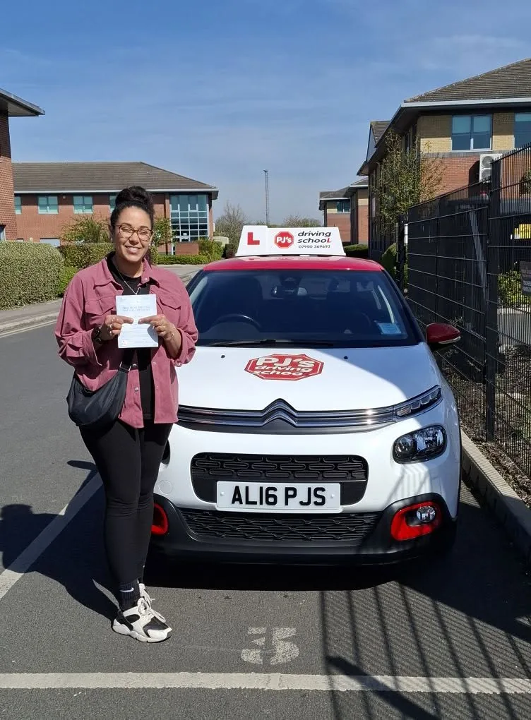 Learner celebrating a driving test pass beside PJ's lesson car