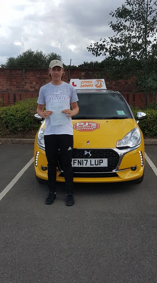 Learner celebrating a driving test pass beside PJ's lesson car
