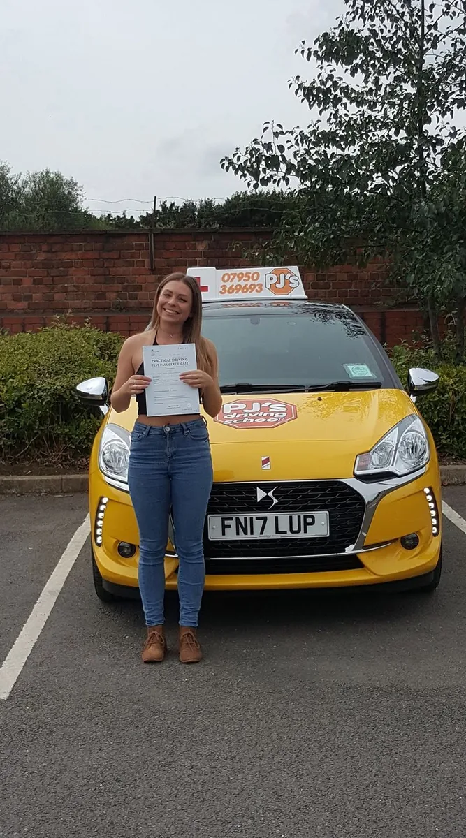 Learner celebrating a driving test pass beside PJ's lesson car
