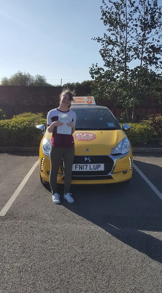 Learner celebrating a driving test pass beside PJ's lesson car