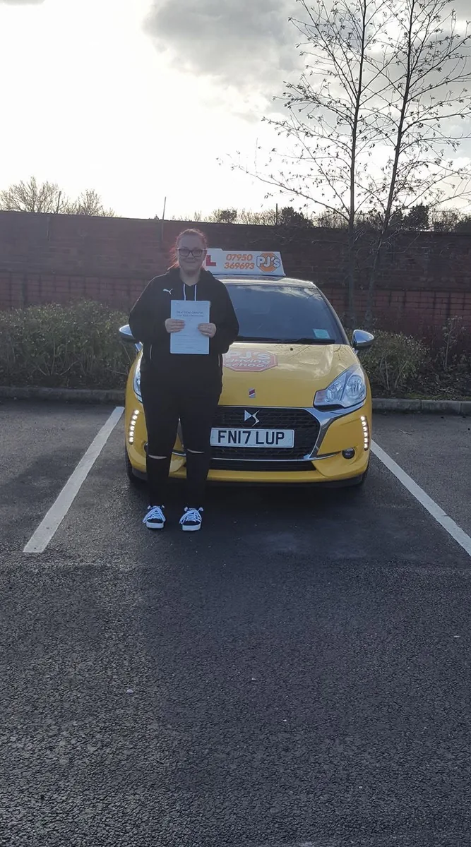 Learner celebrating a driving test pass beside PJ's lesson car