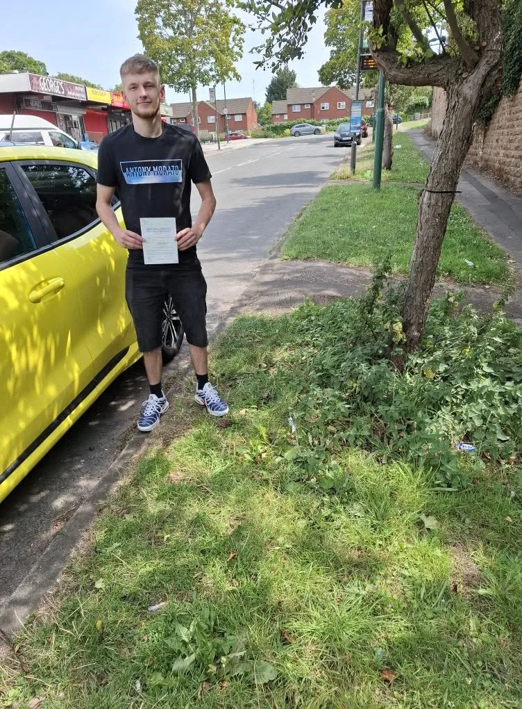 Learner celebrating a driving test pass beside PJ's lesson car
