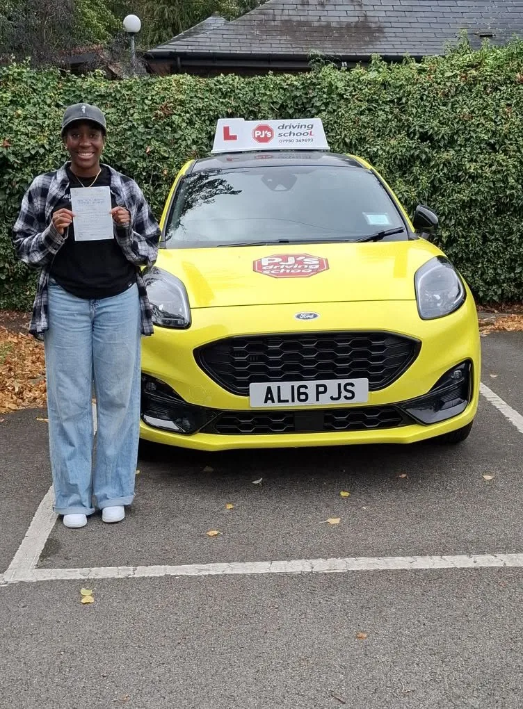 Learner celebrating a driving test pass beside PJ's lesson car