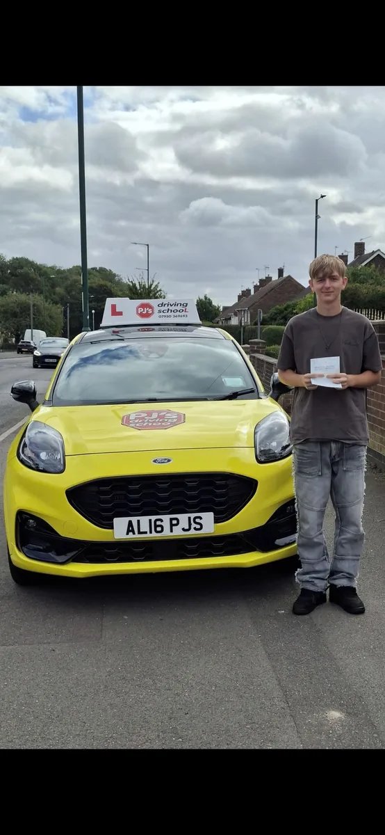 Learner celebrating a driving test pass beside PJ's lesson car