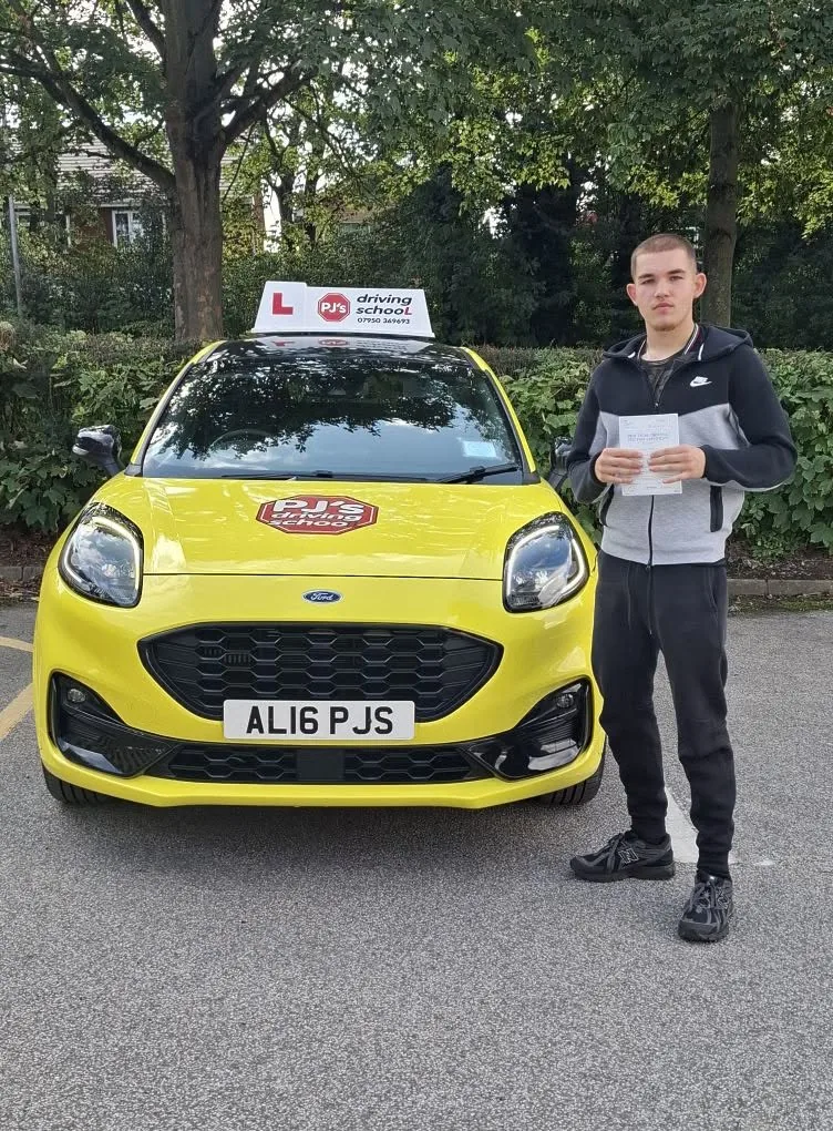 Learner celebrating a driving test pass beside PJ's lesson car