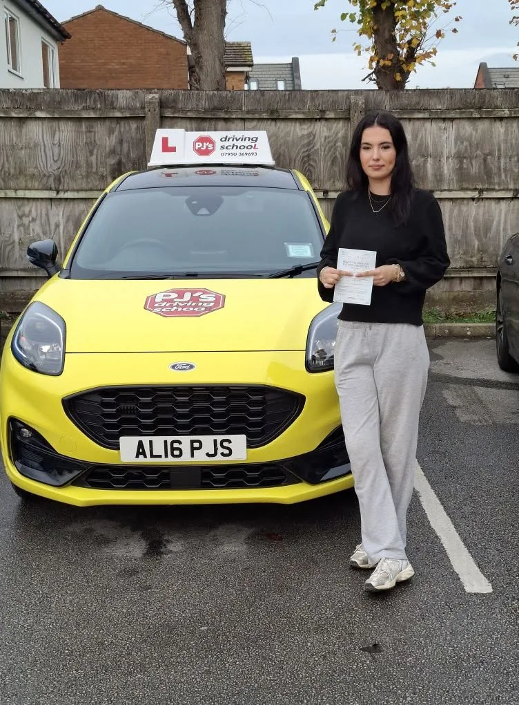 Learner celebrating a driving test pass beside PJ's lesson car