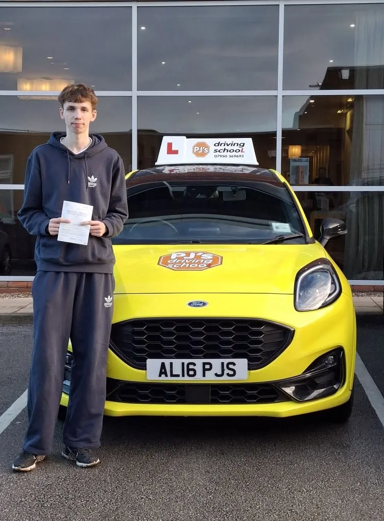 Learner celebrating a driving test pass beside PJ's lesson car