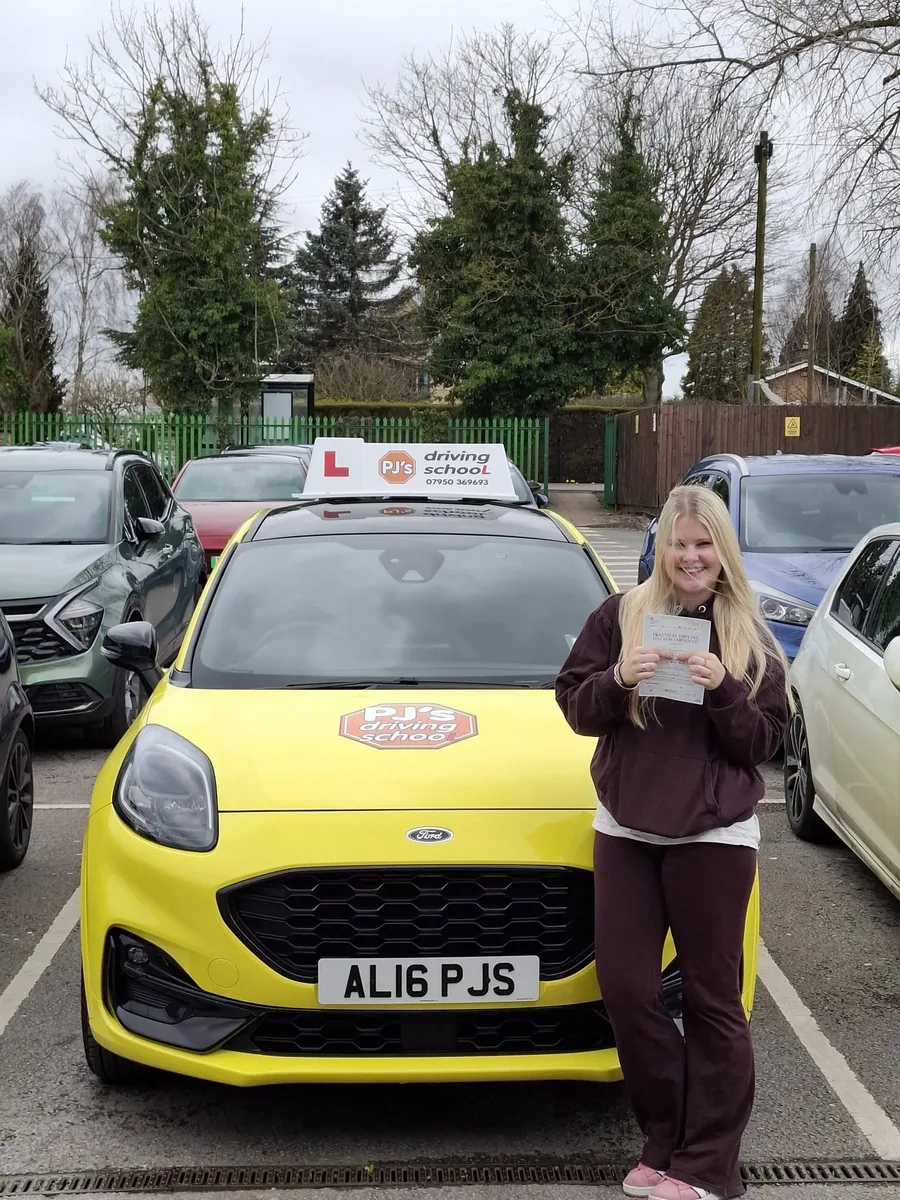 Learner celebrating a driving test pass beside PJ's lesson car