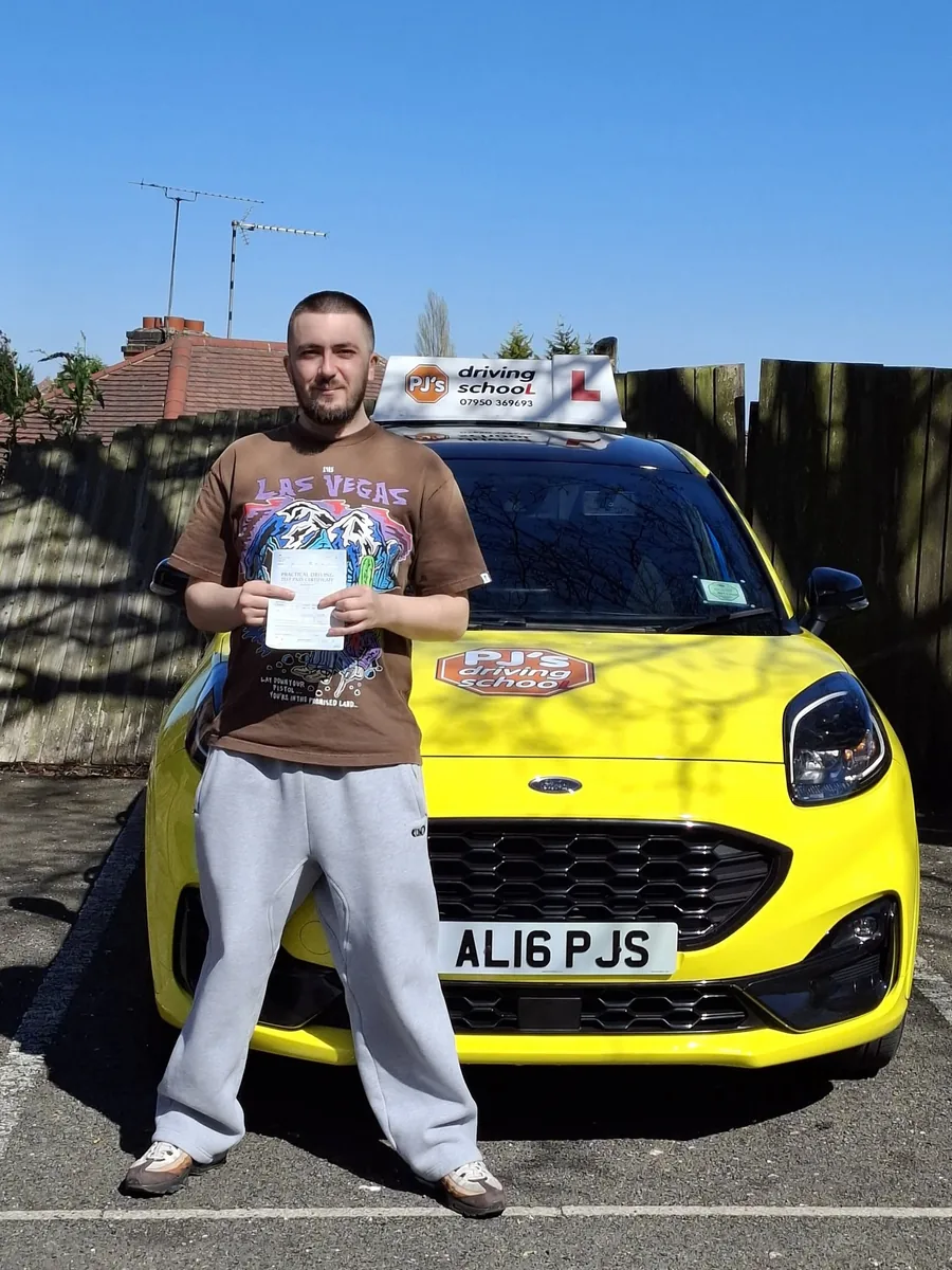 Learner celebrating a driving test pass beside PJ's lesson car