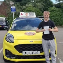 Learner celebrating a driving test pass beside PJ's lesson car