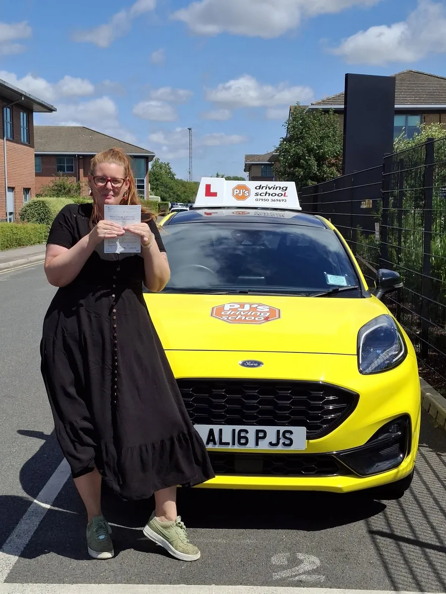 Learner celebrating a driving test pass beside PJ's lesson car